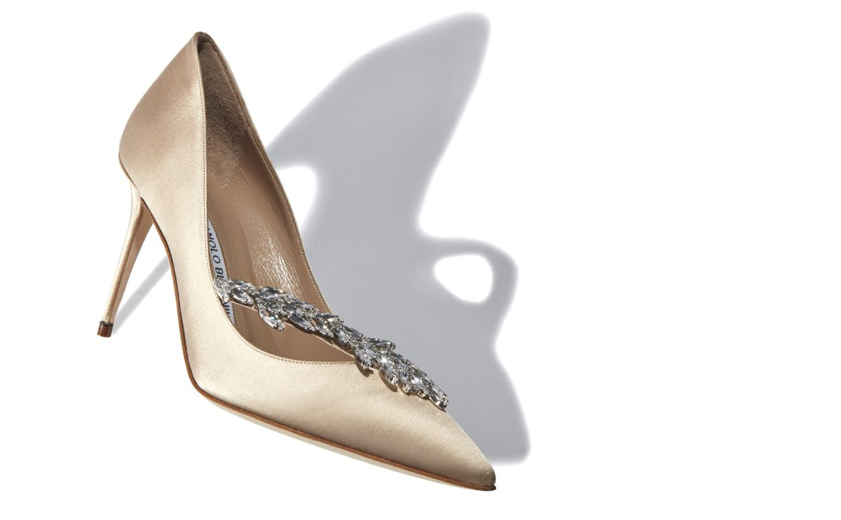 Noelle Bloom Neutral Jewel Buckle Pumps – front three-quarter view showing neutral jewel buckle, pointed toe, satin…